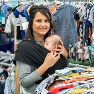 Mom holds daughter who is sleeping in her arms while she shops the local JBF sale.